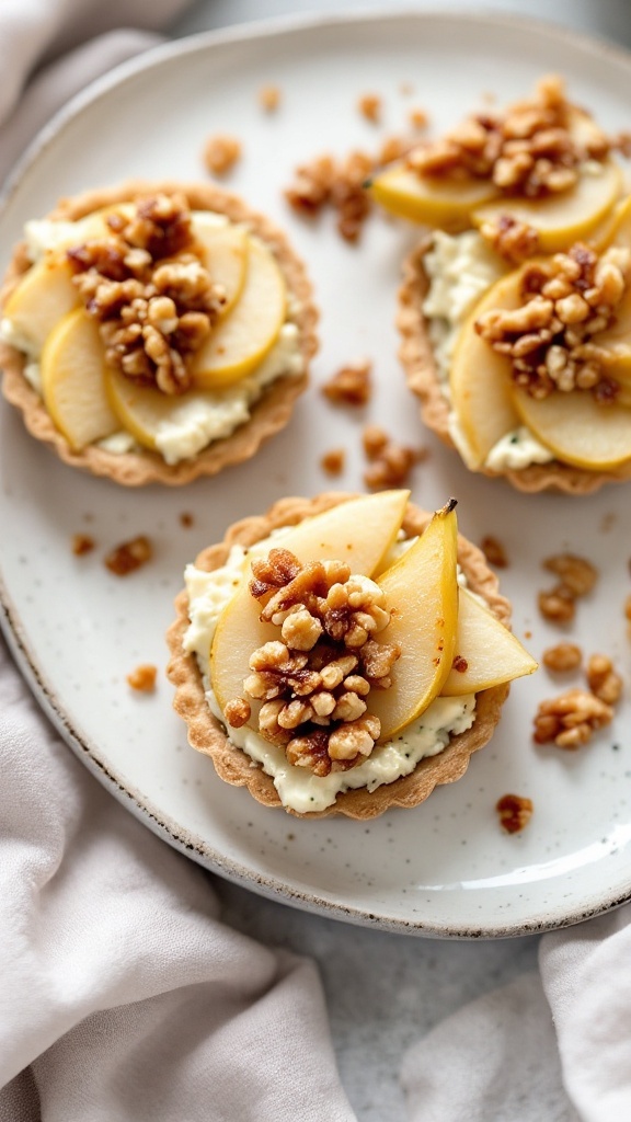 Tarts filled with gorgonzola cheese and pears, topped with candied walnuts on a plate.